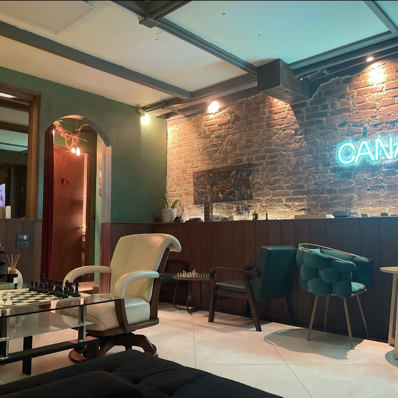 CANABA Club lounge interior — exposed brick, neon sign, vintage furniture